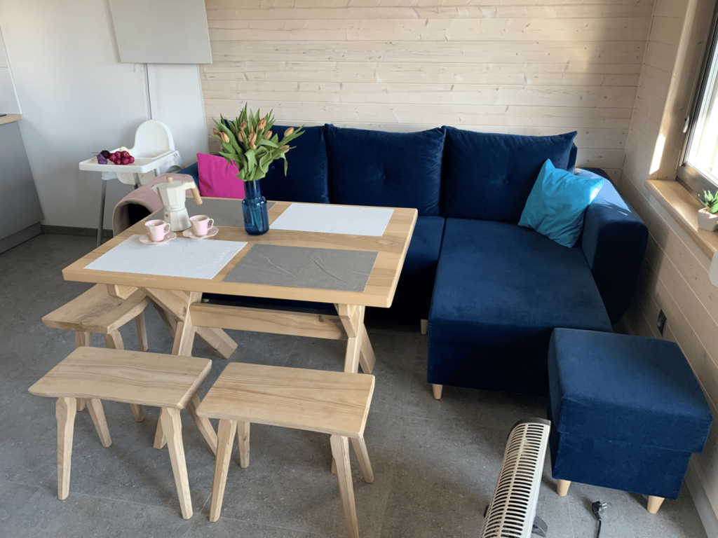 Strefa jadalna z granatową sofą i kwiatami, w komfortowym domku nad morzem.